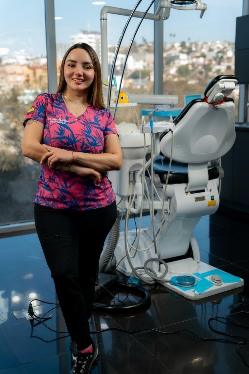 Smiling dental professional standing next to a modern dental chair inside a state-of-the-art dental clinic.